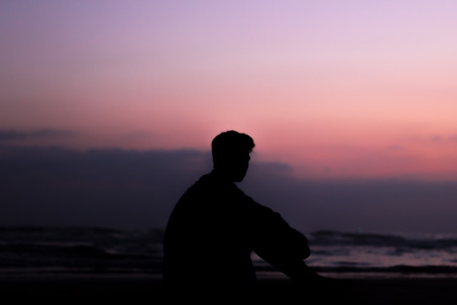 Silhouette of a man in front of a purple sunset.